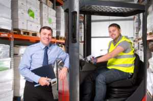Warehouse manager poses with a forklift driver in a distribution center.